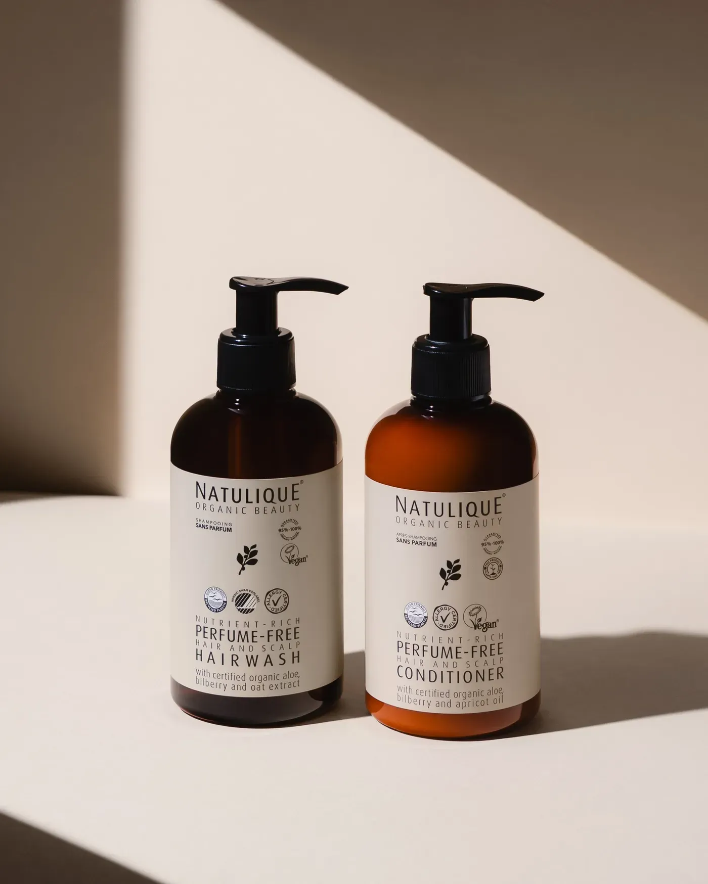 NATULIQUE Perfume-Free Hairwash and Conditioner pump bottles in warm sunlight
