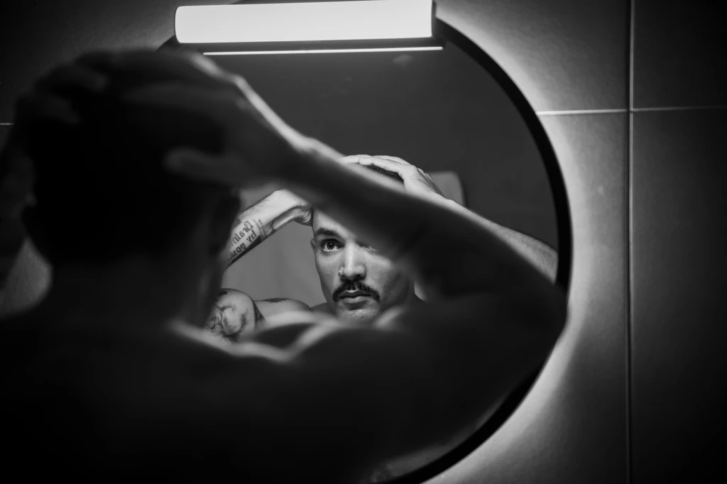 Black and white portrait of a man reflected in a round barbershop mirror