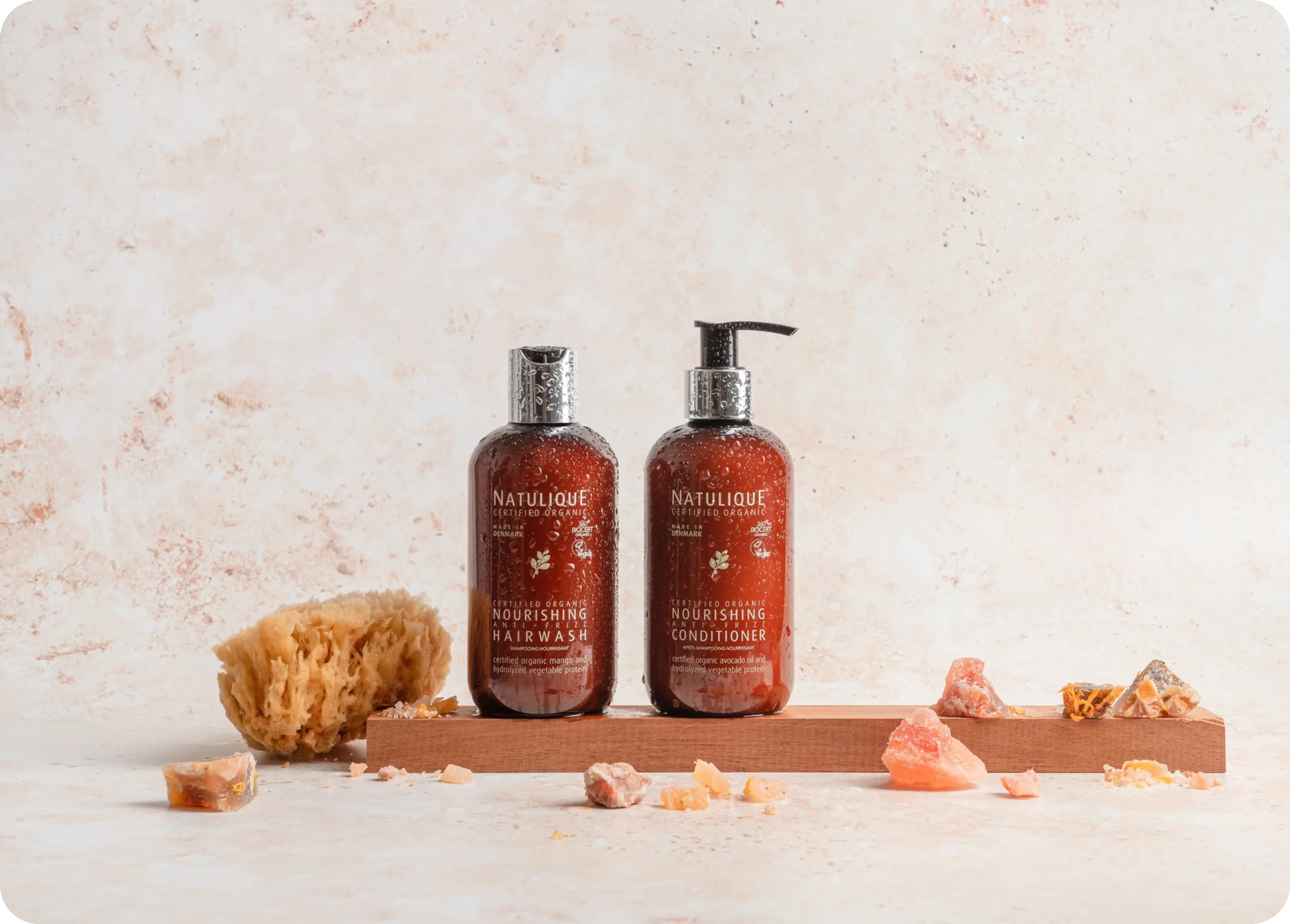 NATULIQUE organic hair care bottles arranged on a wooden tray with natural sponges