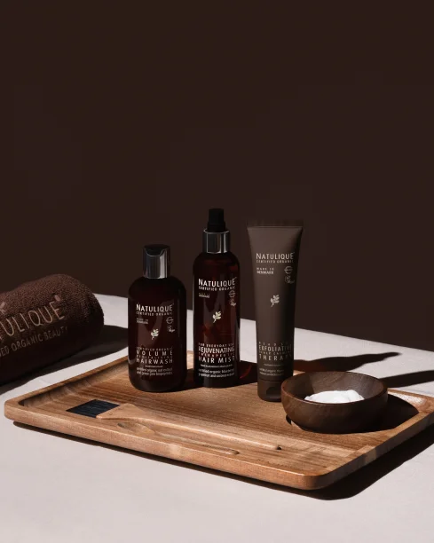 NATULIQUE certified organic hair care and colour products arranged on a wooden board